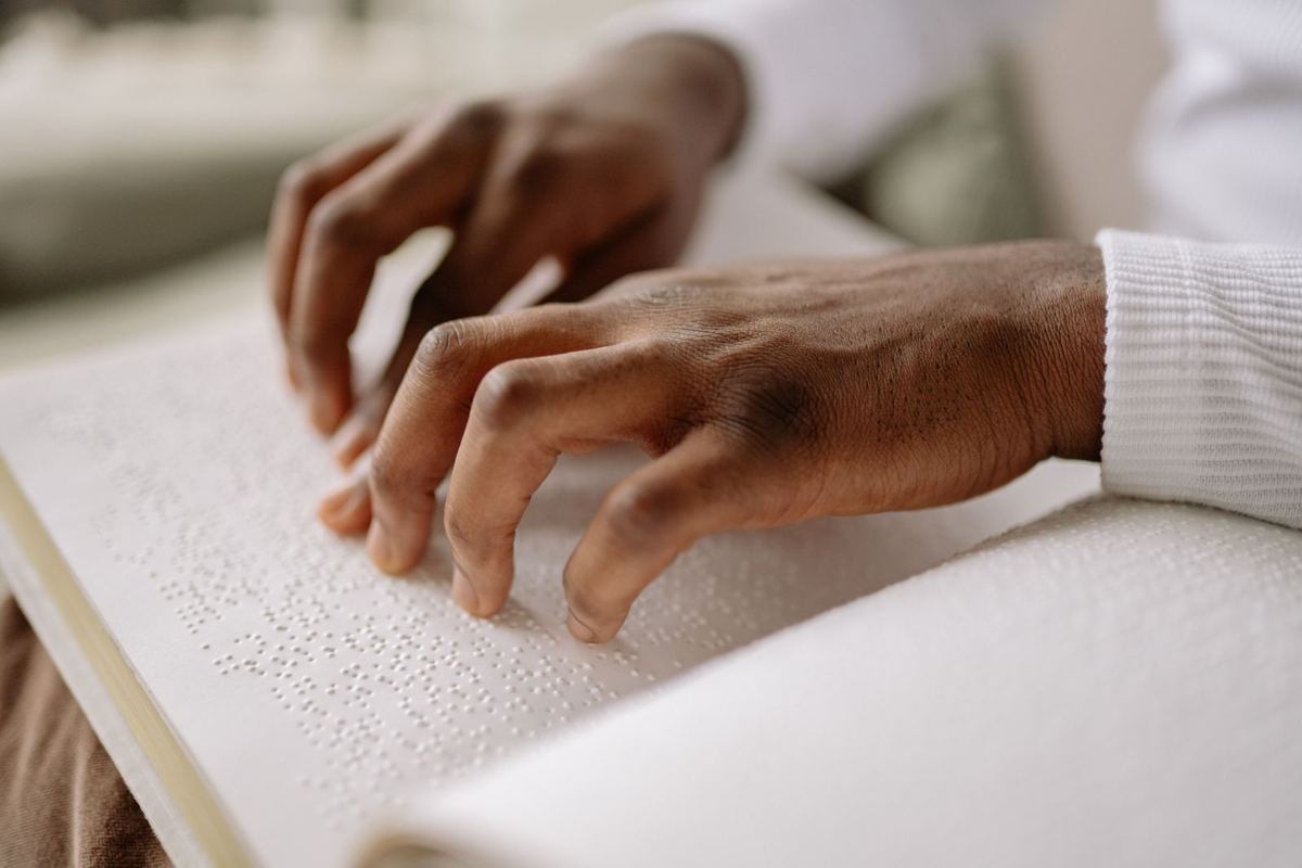 Gros plan sur des mains qui lisent du braille du bout des doigts